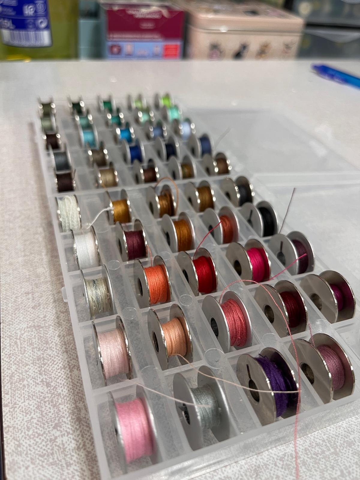 Colección de hilos de costura de colores variados en bobinas, materiales profesionales del taller Arreglos Mónika